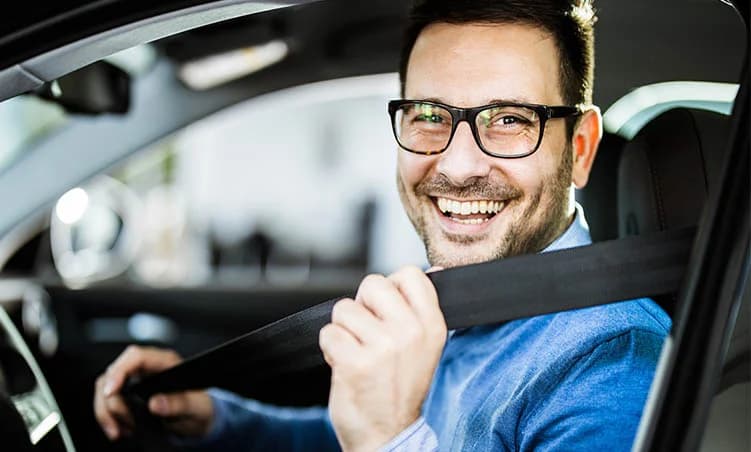 Smiling driver fastening his seatbelt after auto glass service